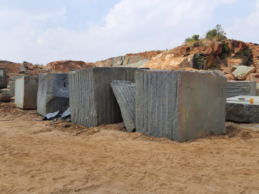 Container-ready grey granite blocks lined up in quarry yard